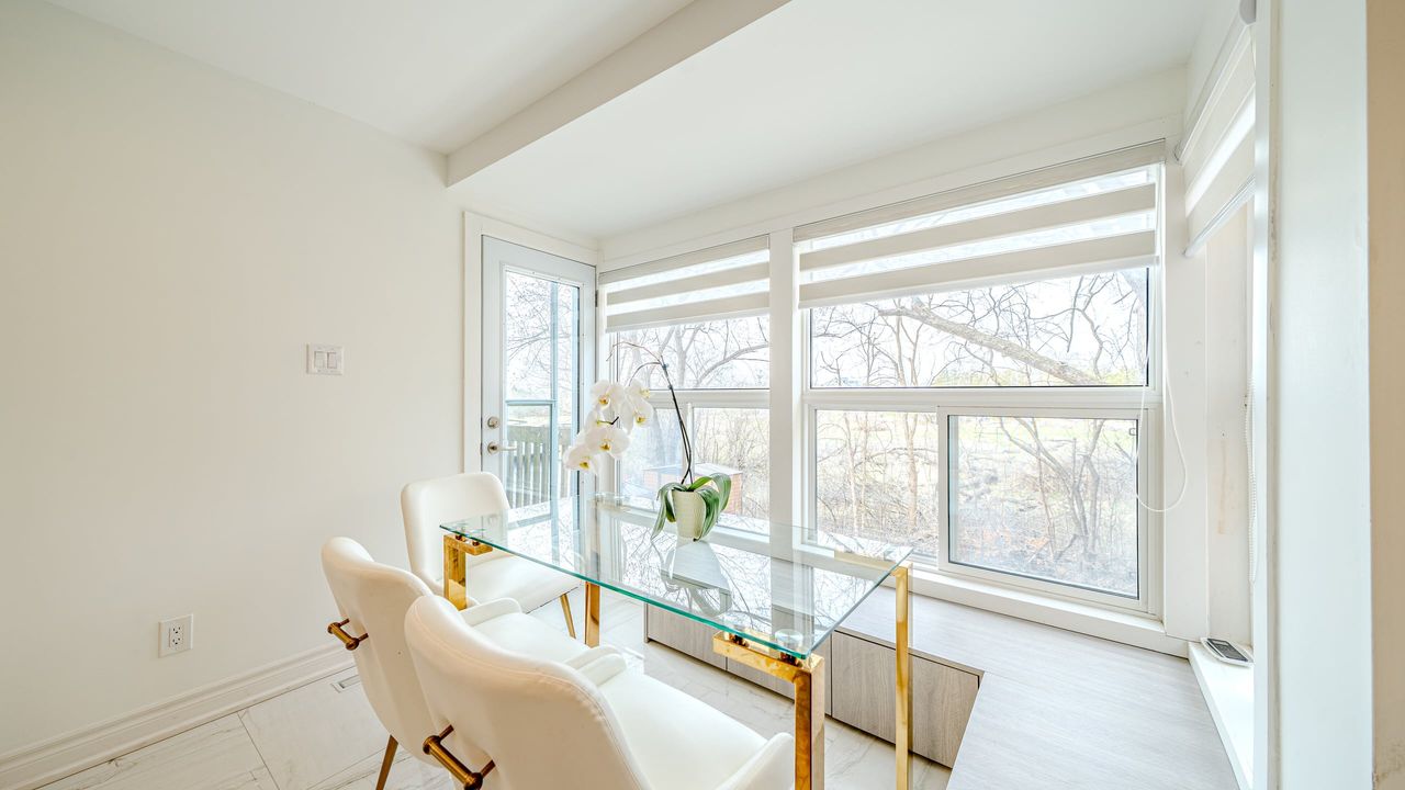 Dining nook with large windows and zebra blinds, a patio door, white tile floor and a glass table with white chairs