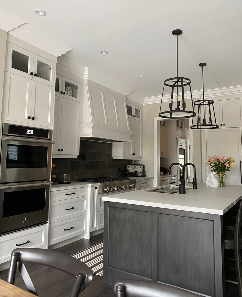 Kitchen with white shaker cabinets, a panelled range hood, a grey stained island and black cage pendant lights