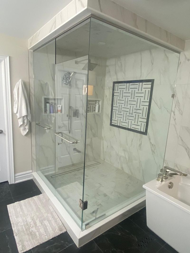 Floor-to-ceiling glass shower with marble-look tile, basketweave mosaic inset and linear drain