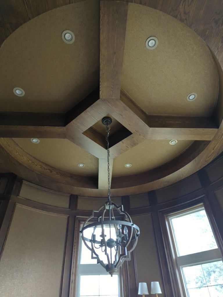 Round room ceiling with stained wood beams in a radial coffer pattern, pot lights and a lantern chandelier