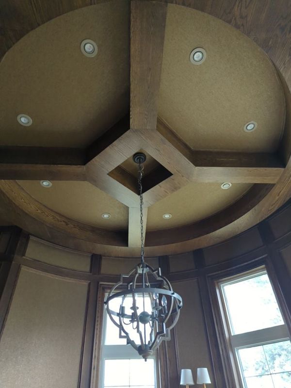Round room ceiling with stained wood beams in a radial coffer pattern, pot lights and a lantern chandelier