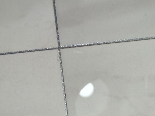 Close-up of white floor tile with silver glitter grout lines