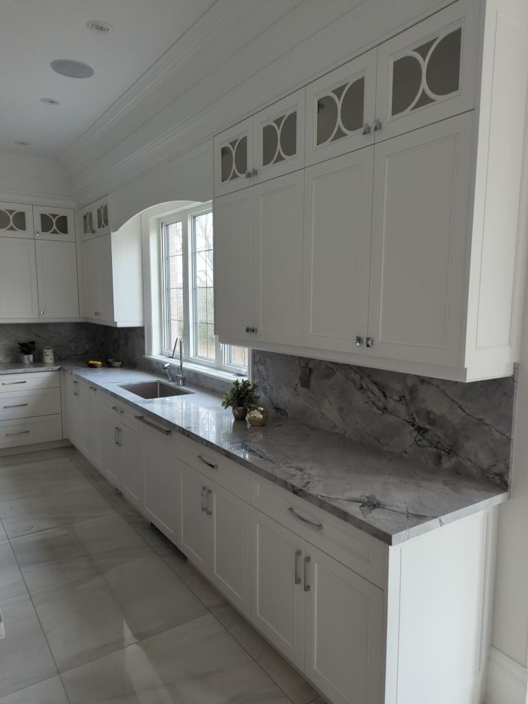 White shaker kitchen run with lattice glass uppers, a quartzite counter and a full height slab backsplash