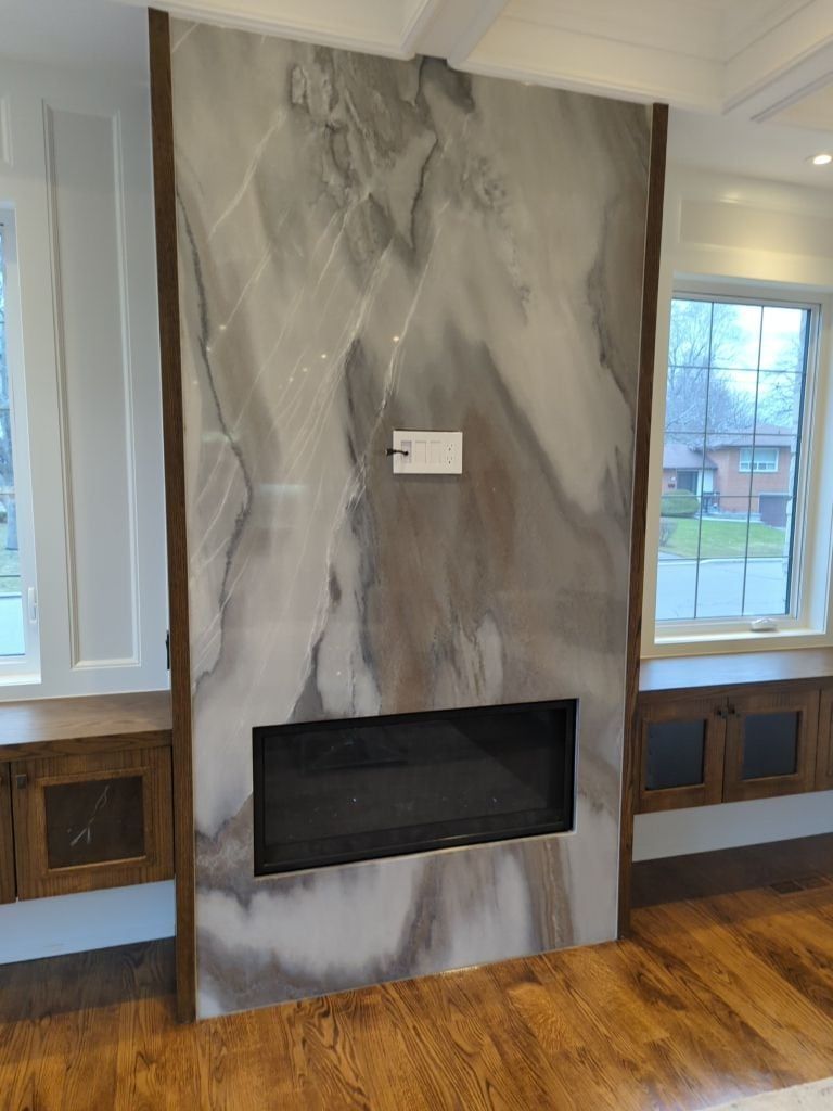 Floor to ceiling stone slab fireplace wall with a linear fireplace, oak trim and built-in window benches