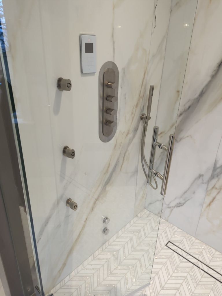 Shower wall with body jets, a thermostatic valve, a hand shower and a digital steam control panel