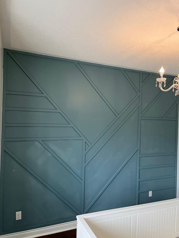 Teal geometric trim accent wall in a nursery with a crystal chandelier