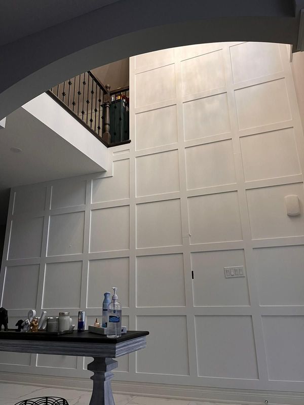 Two-storey white grid panel feature wall in an open foyer below the upstairs landing
