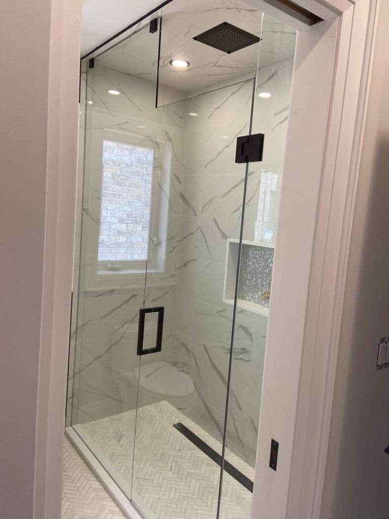 Glass walk-in shower with marble-look porcelain, herringbone floor, linear drain and matte black hardware
