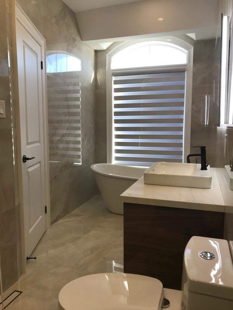 Bathroom with freestanding tub under an arched window, vessel sink vanity and polished porcelain floor