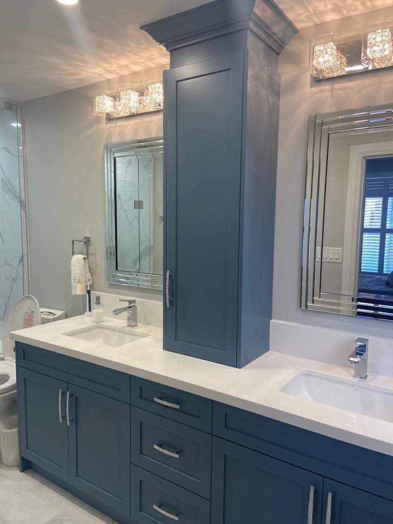 Double vanity in slate blue shaker cabinets with white quartz top, centre tower and bevelled mirrors
