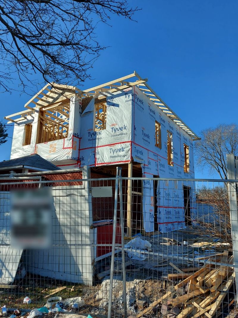 A house wrapped in housewrap, with the roof trusses on