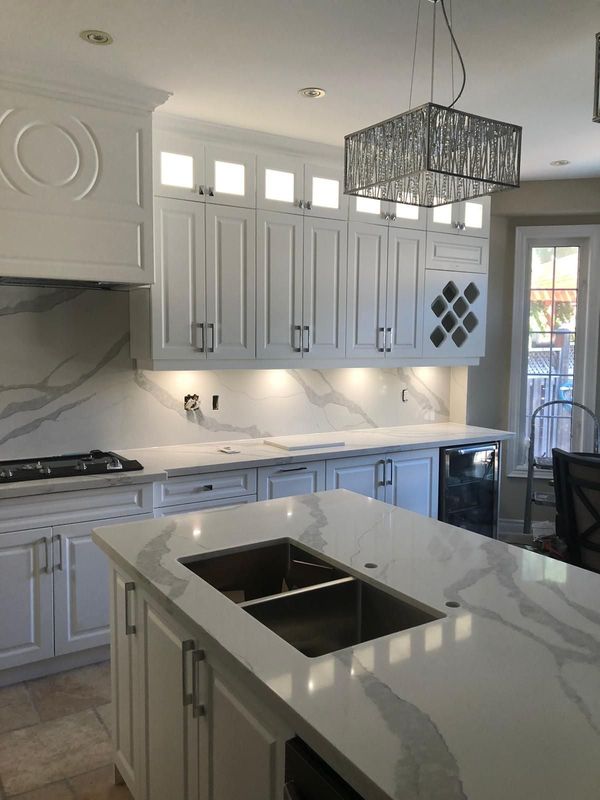 White raised panel kitchen with a quartz island, full-height quartz backsplash and wine rack