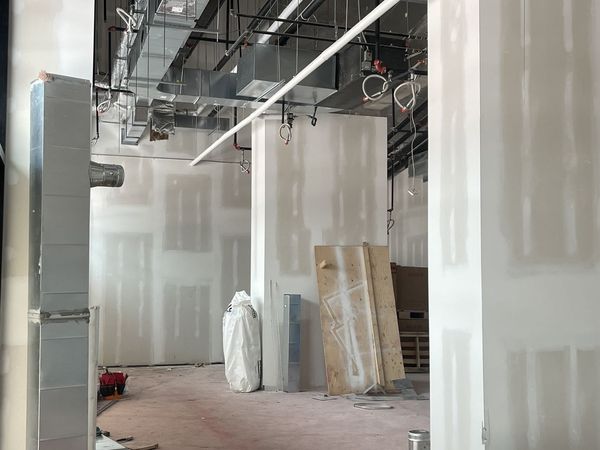 Taped drywall walls and a column under exposed ductwork