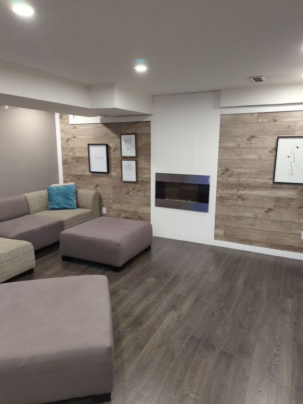 Basement lounge with barnwood-look accent walls beside a wall-mounted electric fireplace