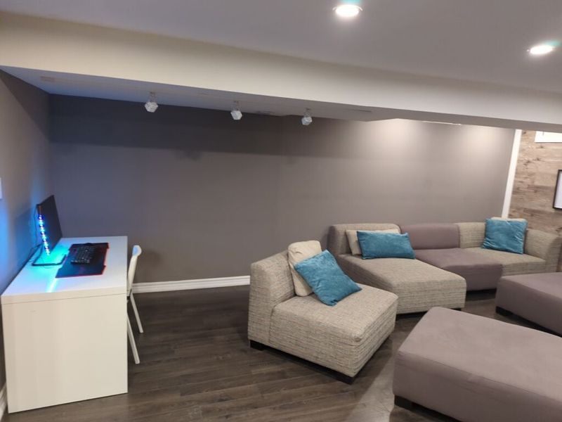 Basement with grey walls, track lighting and laminate flooring around a desk nook