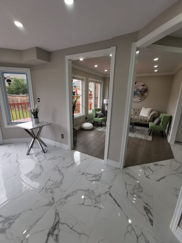 Marble-look porcelain tile hallway opening to a living room with wood-look flooring