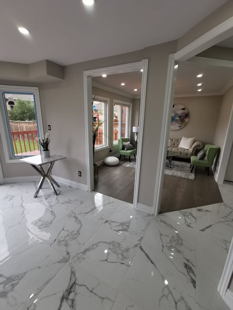 Marble-look porcelain tile hallway opening to a living room with wood-look flooring